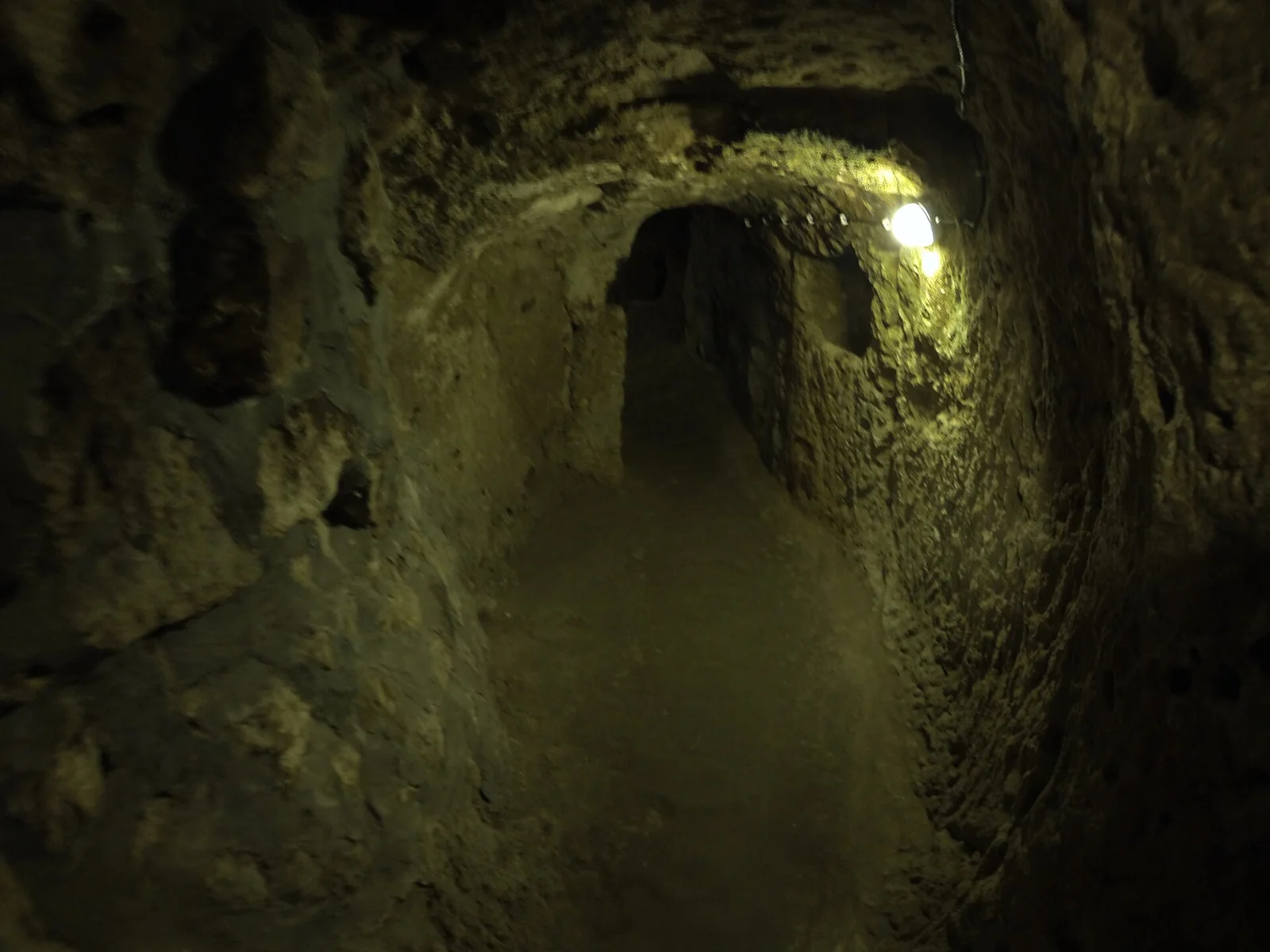 A dark, narrow passage with a modern lamp inside Derinkuyu
