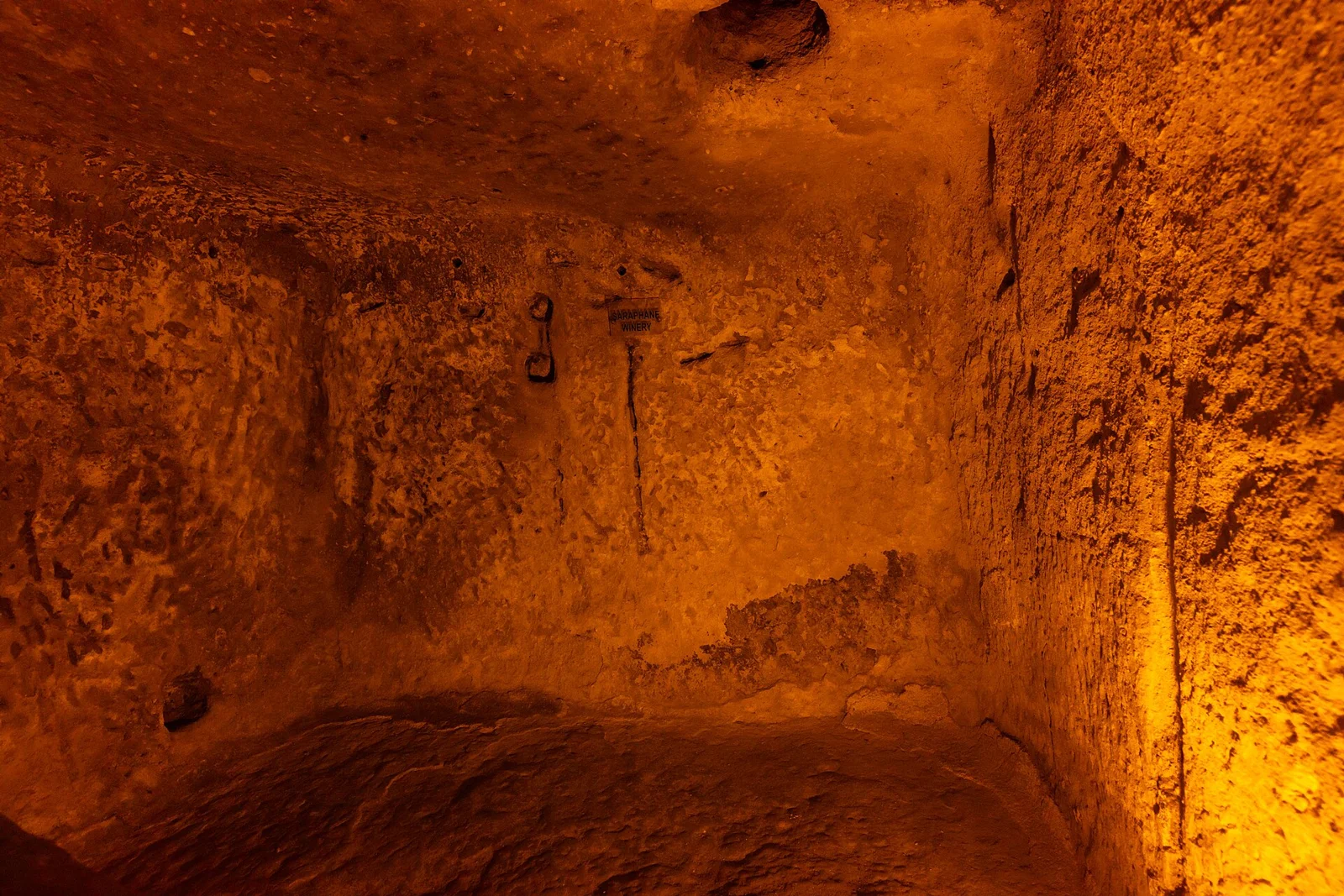 Rock-cut chamber at Ozkonak with a museum winery sign